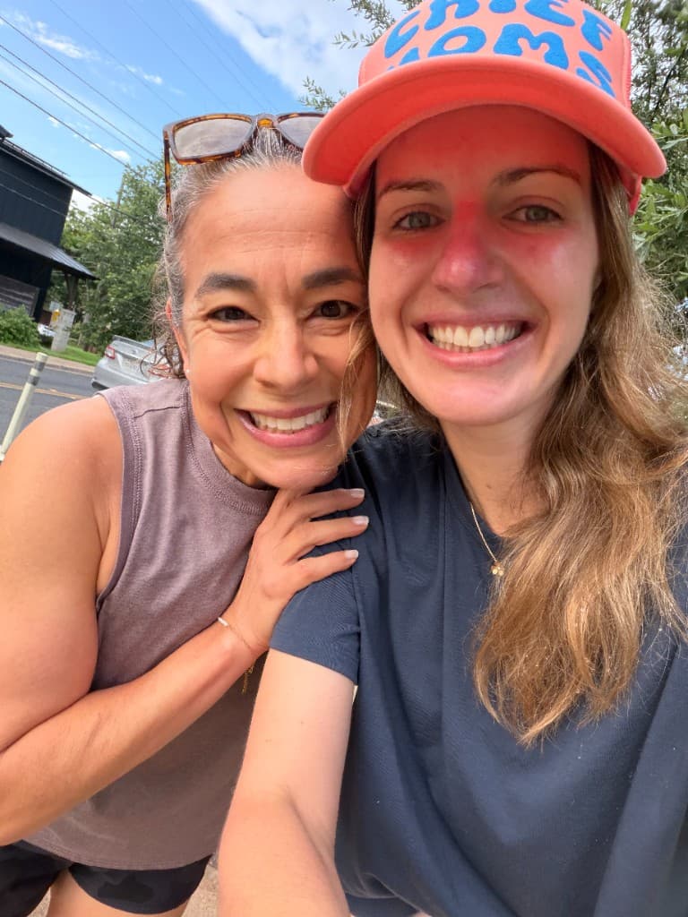 Two moms smiling together on a Chief Moms walk, one wearing a Chief Moms trucker hat