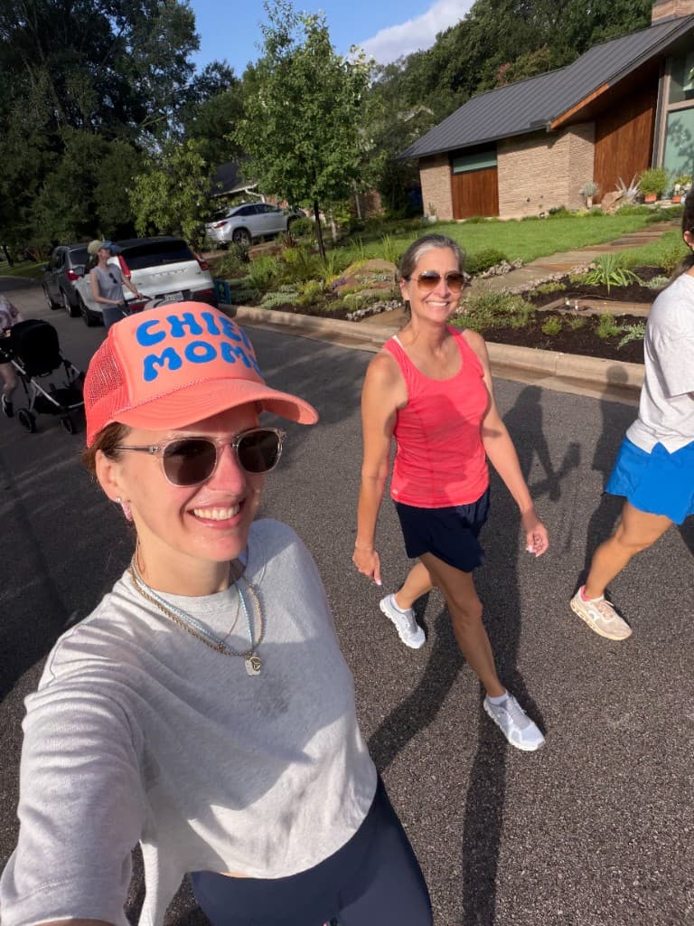 Smiling moms on a Chief Moms walk wearing Chief Moms hats in a sunny neighborhood